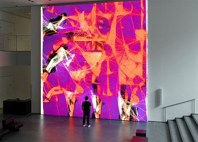 Large digital art installation featuring vibrant abstract patterns in pink, purple, and orange, displayed on a high-resolution LED screen in a modern gallery setting.